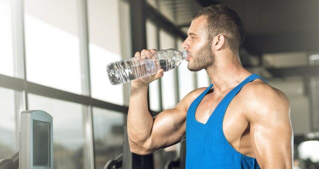 41601728 - young adult man drinking bottle of water on threadmill in gym.